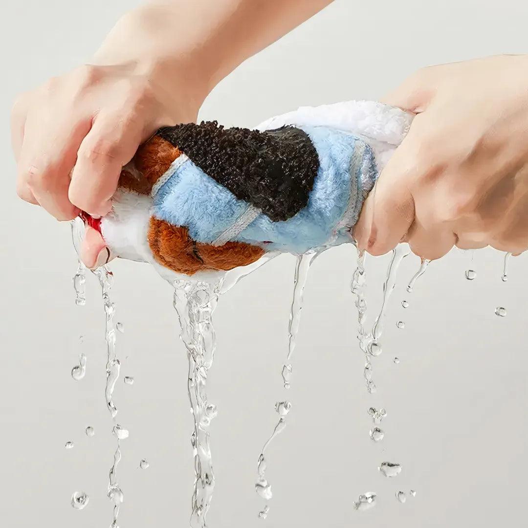 Blue dachshund-shaped coral fleece towel being wrung out, showing high water absorbency