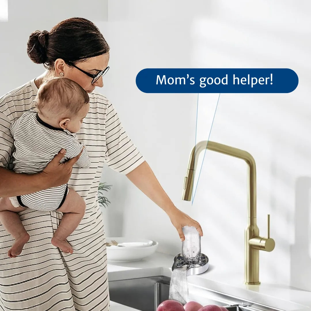 A mother holding her baby with one arm while effortlessly cleaning a cup with the glass rinser using the other hand, showcasing ease of use and convenience for busy parents.