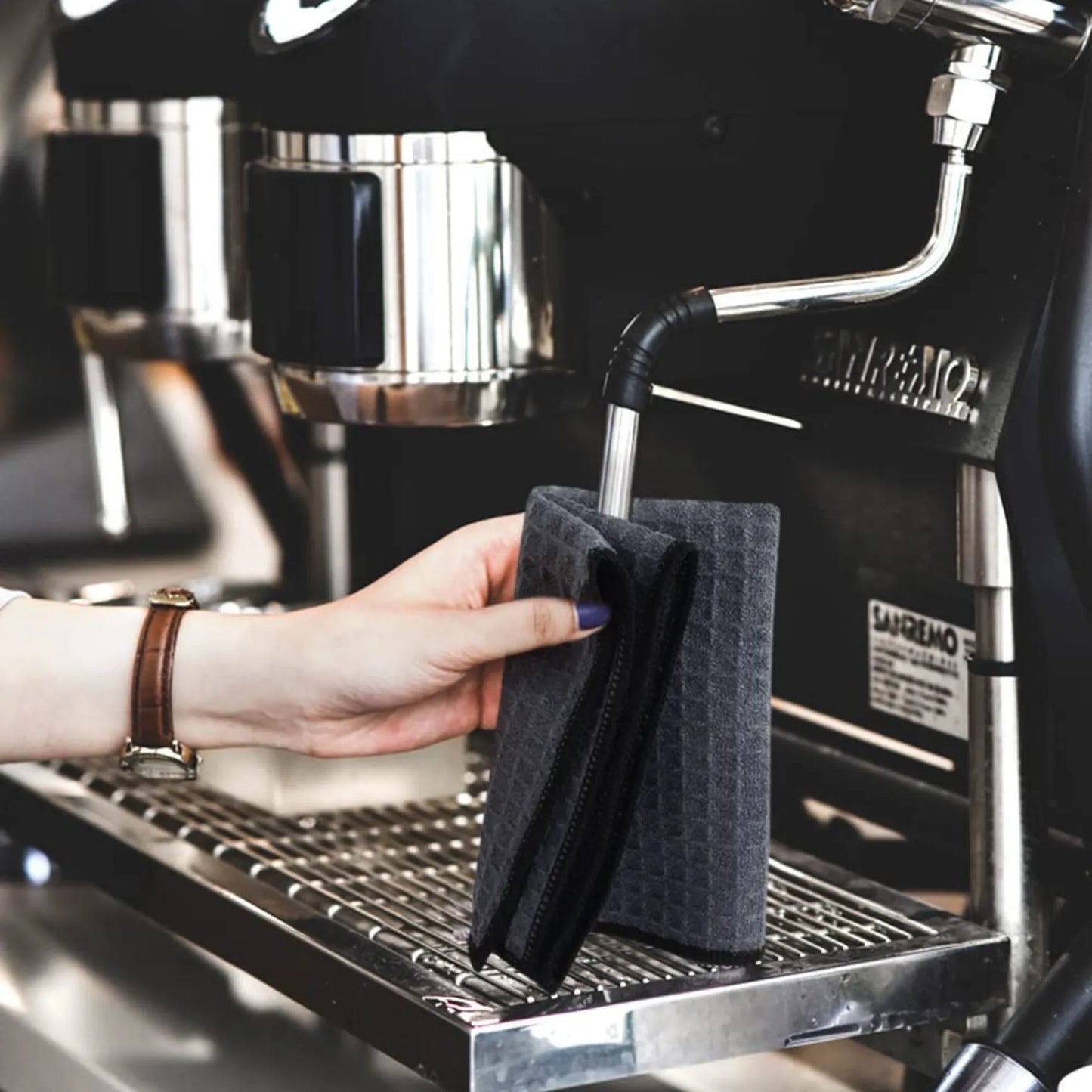 A person cleaning a coffee machine using a waffle pattern microfiber cloth, effectively removing dirt and grease for a spotless finish. Perfect for versatile cleaning tasks around the home