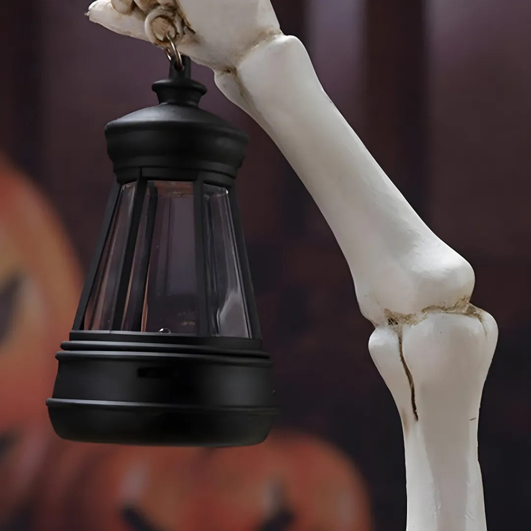 Close-up of Halloween solar garden lamp with skeleton hand holding black lantern. Features bone textures and glass enclosure for spooky outdoor decor.