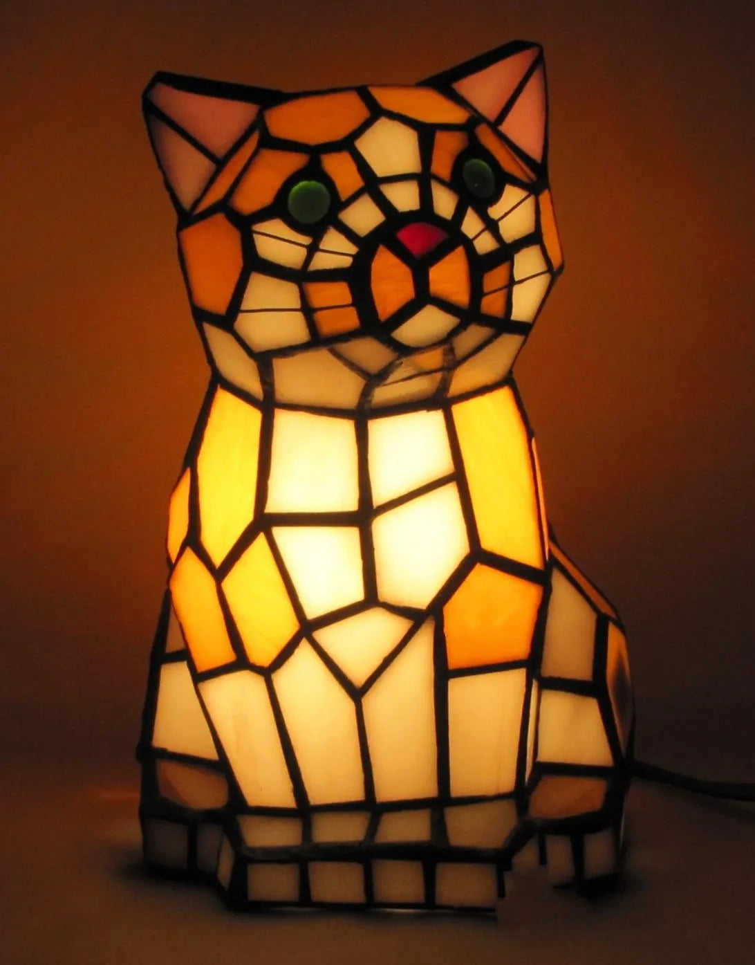 Stained glass cat-shaped lamp on a dark background