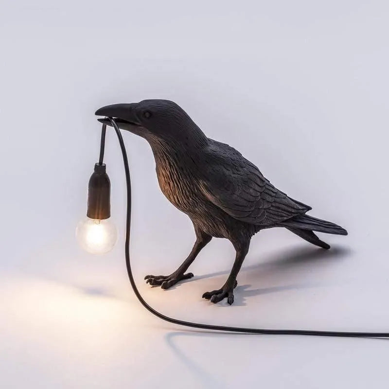 Black bird-shaped lamp with a light bulb on a white background