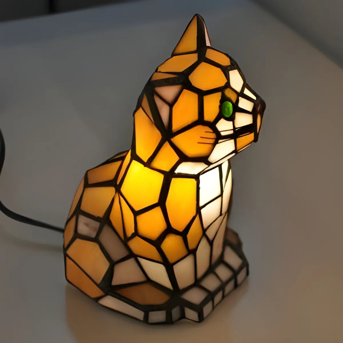 Tiffany cat lamp gift with stained glass panels in amber and cream, geometric black leading, and glowing green eye, creating warm ambiance.
