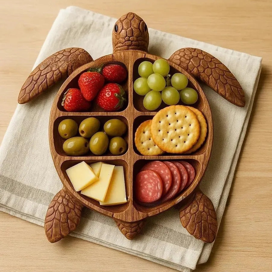 Wooden turtle-shaped platter with compartments filled with fruits, vegetables, and snacks on a beige napkin.
