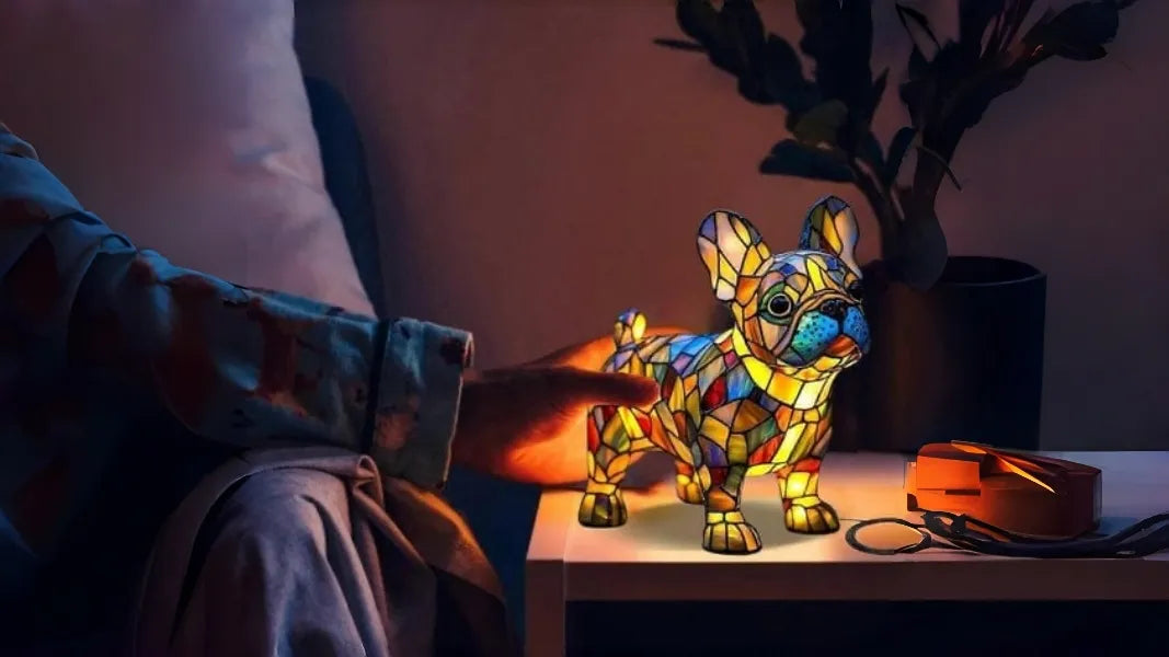Colorful stained glass dog lamp on a table with a person's hand holding it.