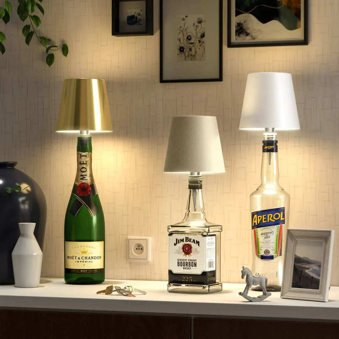 Set of three wireless bottle lamps featuring Moët & Chandon champagne, Jim Beam bourbon, and Aperol bottles with gold, beige, and white lampshades.