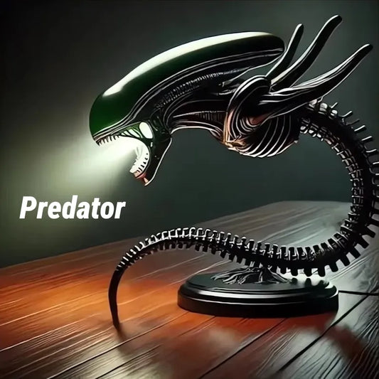 Xenomorph alien desk lamp with glowing mouth and predator text, placed on wooden desk with dark background.