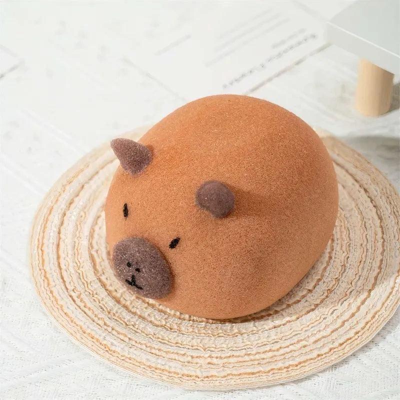 Brown capybara-shaped PU sponge with round body, dark ears and nose on woven mat