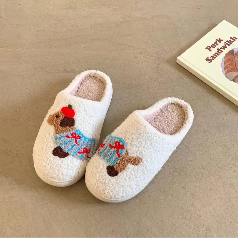A pair of white fuzzy memory foam house shoes featuring a cute dachshund with blue stripes and red bows, offering a soft and cozy cotton feel.
