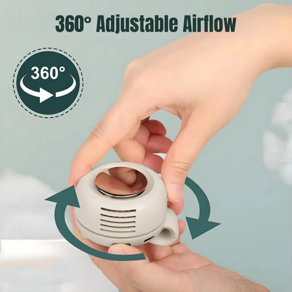 Hand holding white portable clip-on mini fan with "360° Adjustable Airflow" text and rotation arrows, showing full directional control on soft blue background.