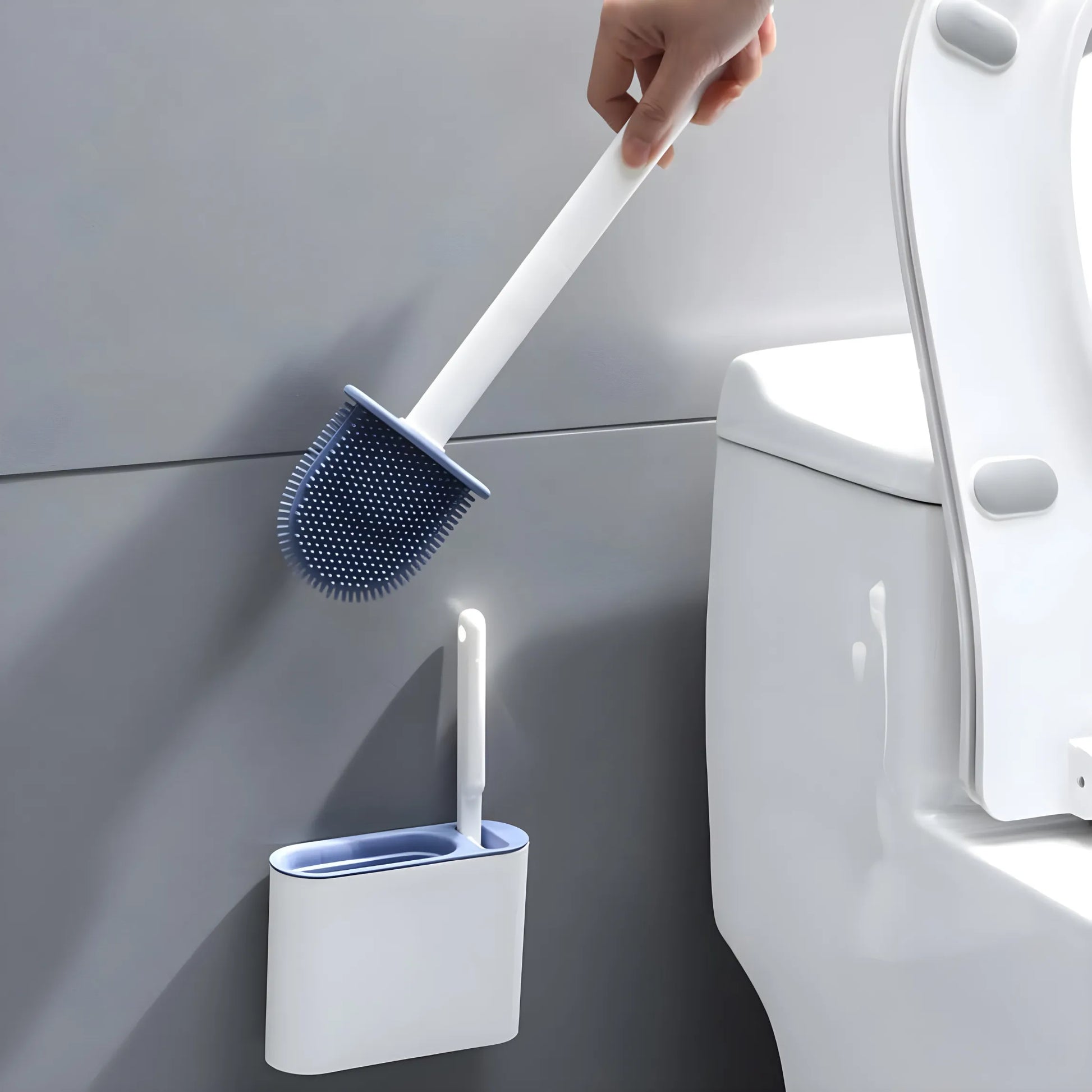 A silicone toilet brush with a minimalist design being placed into a wall-mounted holder next to a toilet. Saves floor space and blends seamlessly into modern bathrooms.