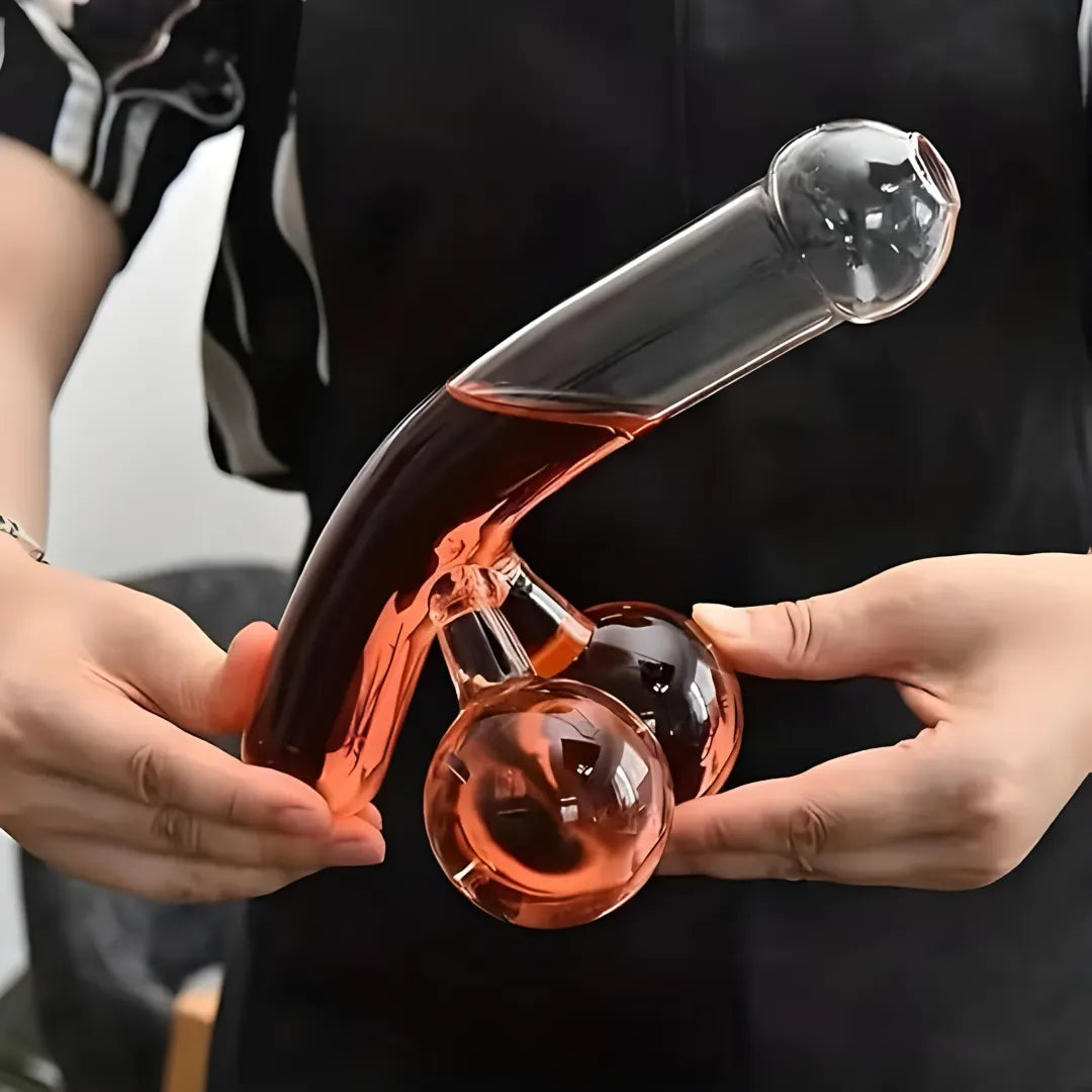 Clear glass decanter with liquid held by two hands against a blurred background