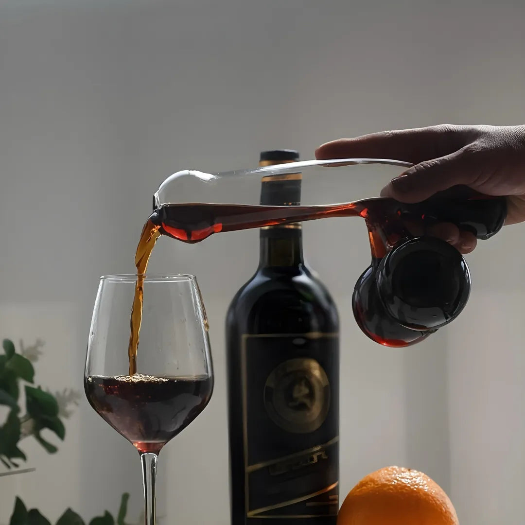 Person pouring dark liquid from a bottle into a glass with a blurred background