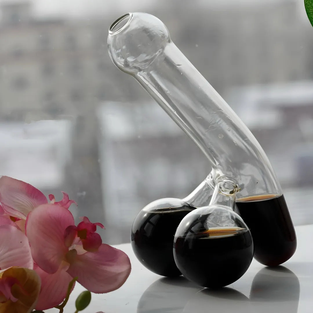 Funny decanter with dark liquid among pink orchids against cityscape. Humorous glassware for bar decor.