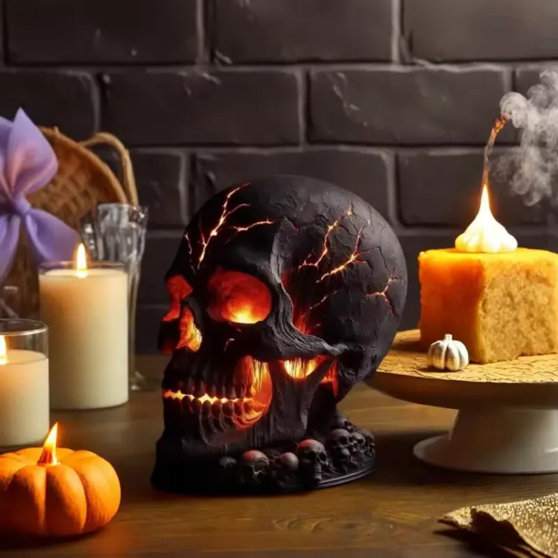 Decorative skull with glowing eyes on a table with candles and pumpkins, against a brick wall background.