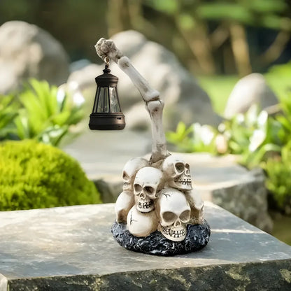 Solar-powered Halloween garden lamp with skeletal arm holding black lantern atop detailed skull pile. Ideal for eco-friendly spooky outdoor lighting in garden settings.