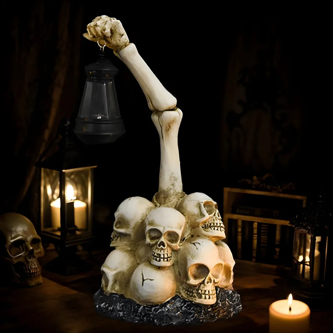 Solar-powered Halloween garden lamp with skeleton hand holding lantern atop skull pile. Features solar panel for automatic night lighting in outdoor Halloween decor.