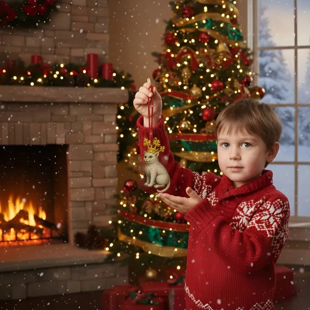 Child in a red sweater holding a ornament in front of a Christmas tree and fireplace.