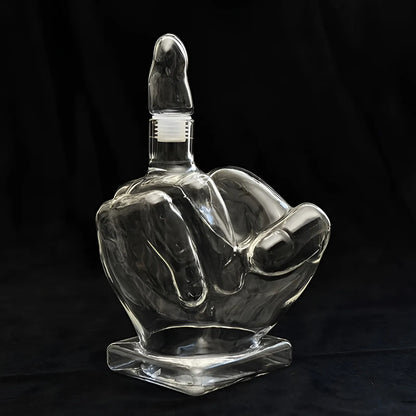 Clear glass middle finger decanter with stopper isolated on black background. Hand-shaped liquor bottle for whiskey or bar decor.