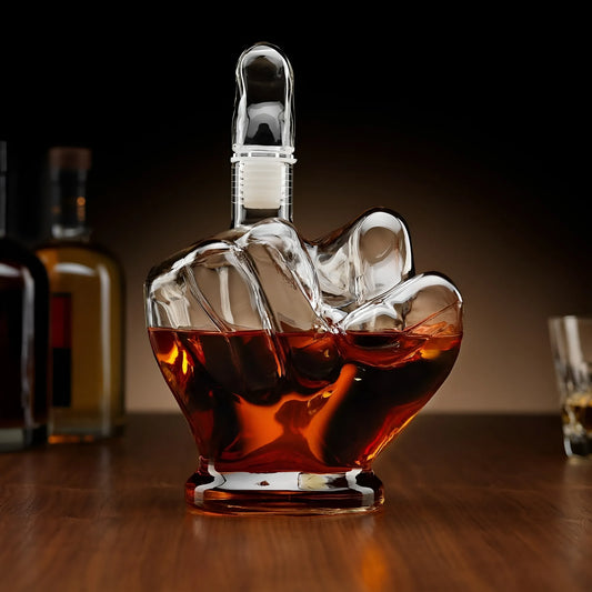 Glass middle finger decanter filled with amber whiskey on wooden table. Unique hand-shaped liquor bottle for bar decor and gift ideas.