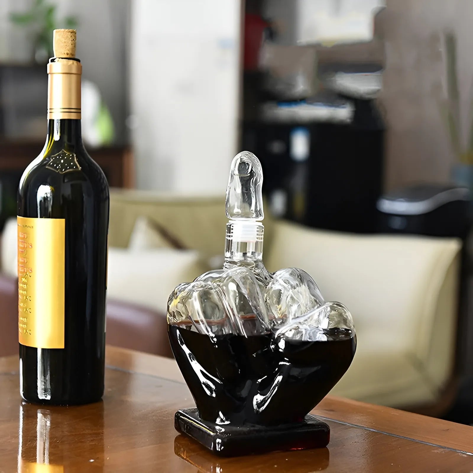 Middle finger decanter filled with red wine next to a bottle on a wooden table. 