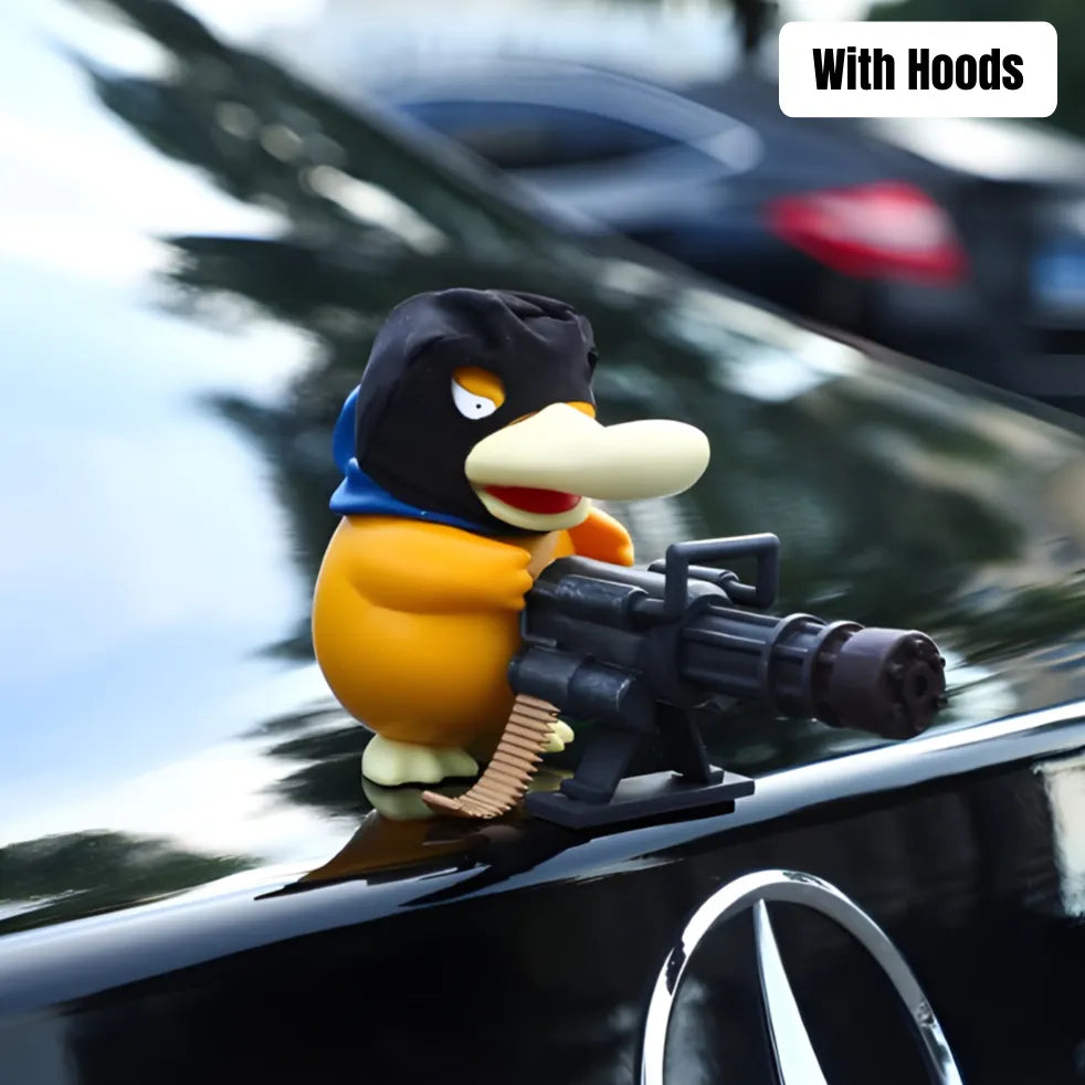 Psyduck car ornament with hoods wears black hoodie and holds toy machine gun on Mercedes-Benz hood with blurred traffic background.