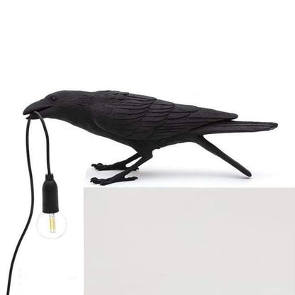 Black bird-shaped lamp with a bulb on a white background