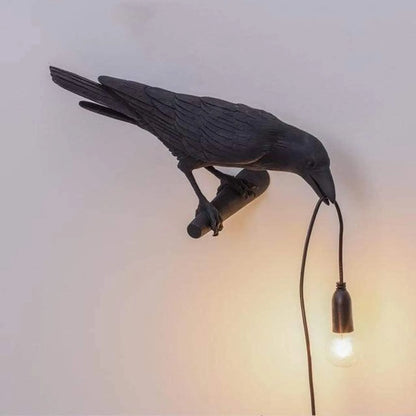 Decorative wall light shaped like a bird with a bulb, on a plain background.