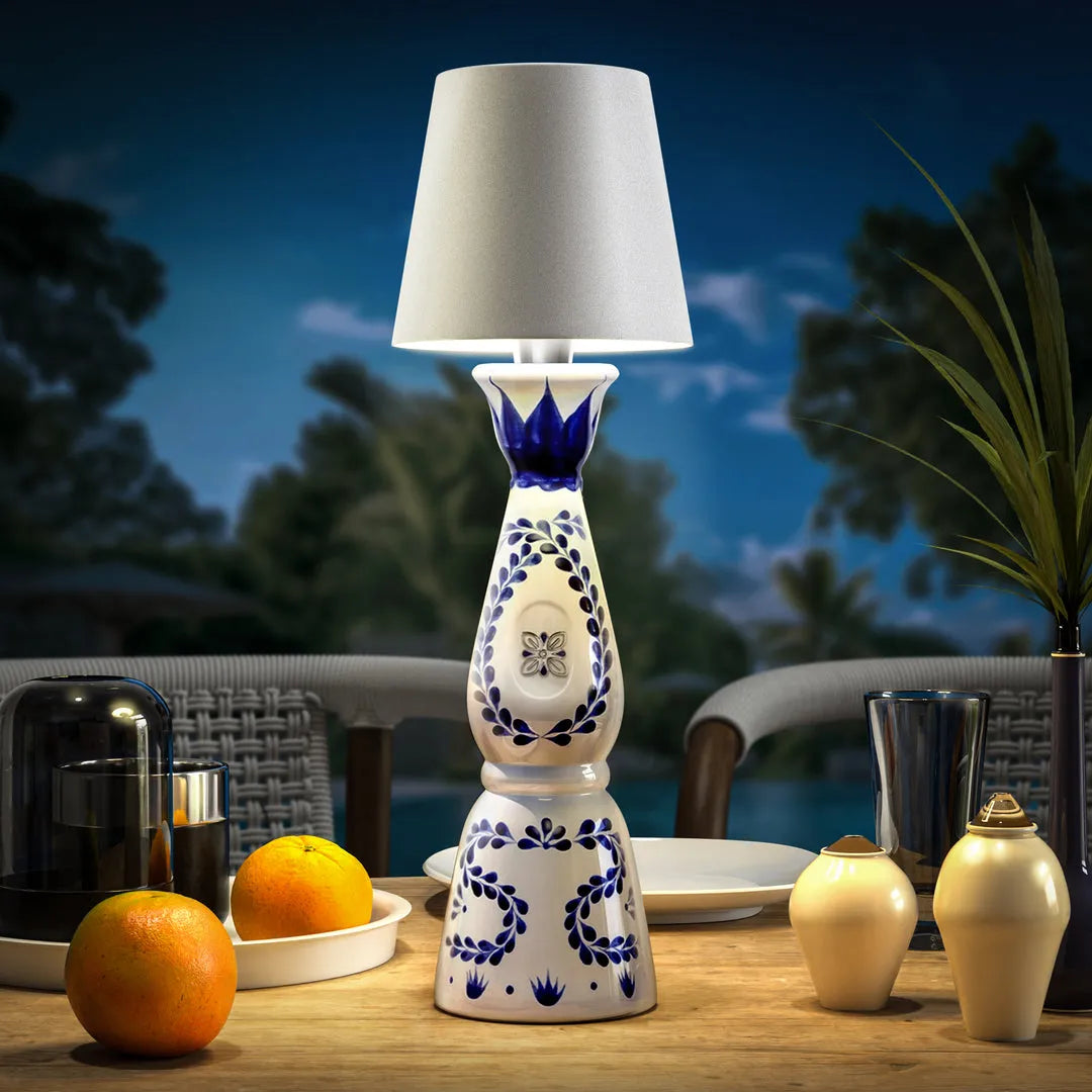 Wireless rechargeable bottle lamp with elegant blue and white floral pattern, placed on a wooden patio table with oranges and glassware.