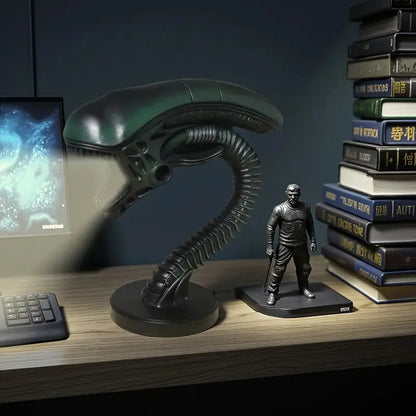 Alien movie prop and figure on a desk with books and computer monitor in the background