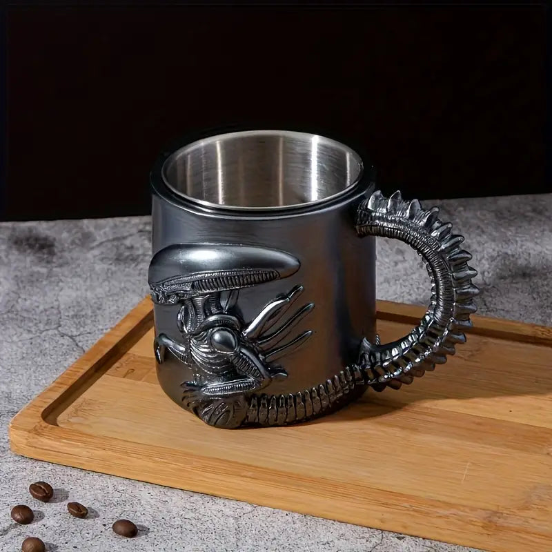 Metallic mug with alien design handle on a wooden board